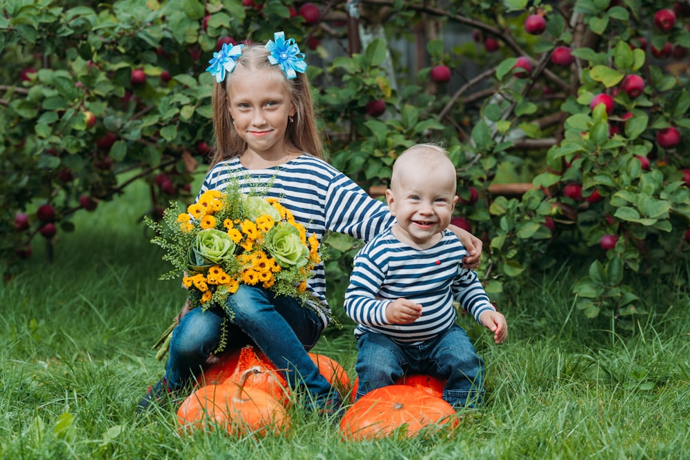 a person and a baby sitting in a pumpkin patch
