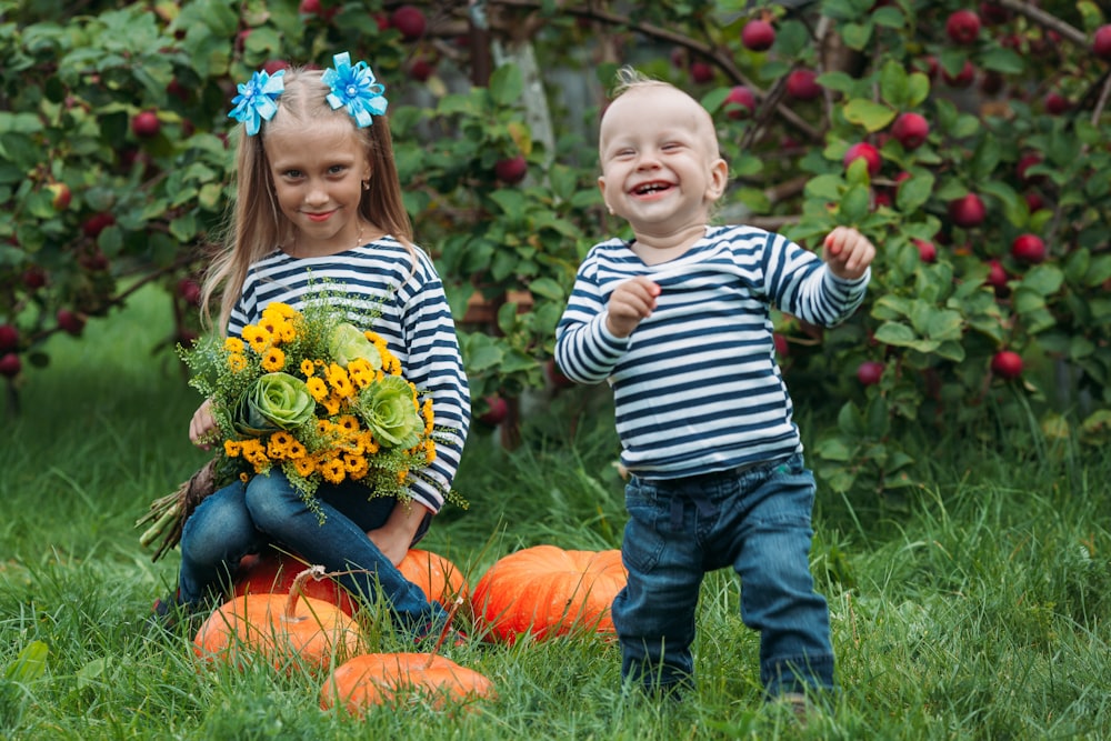 a boy and girl in a field of grass with flowers