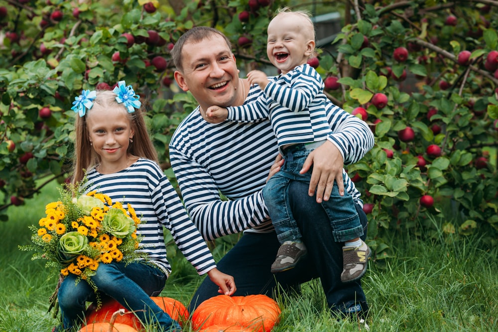a woman and two children sitting in a pumpkin patch