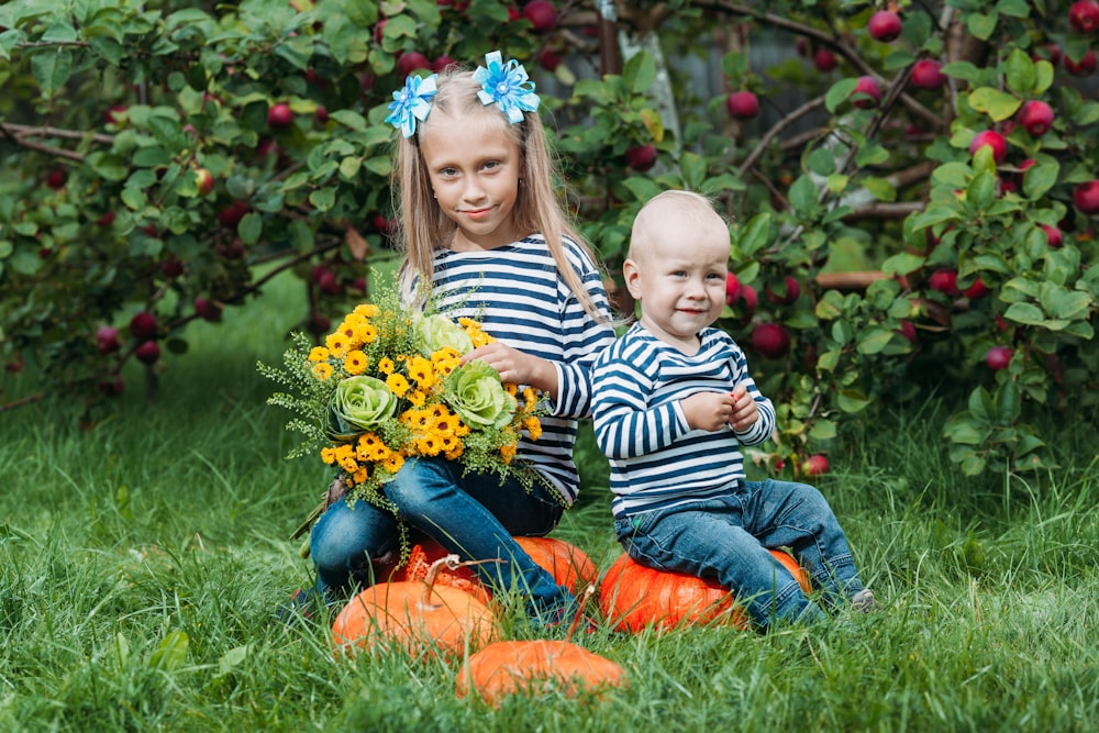 a person and a baby sitting in a grassy area with flowers