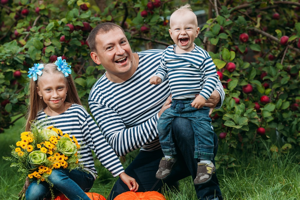 a person and two children sitting on a bench in front of a tree