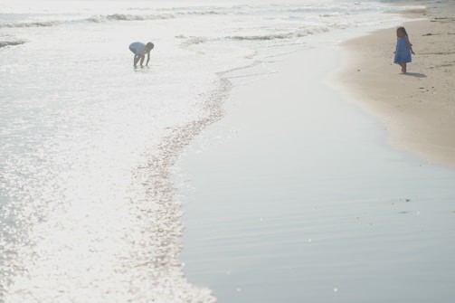 Children playing by the seaside, with waves gently rolling in.