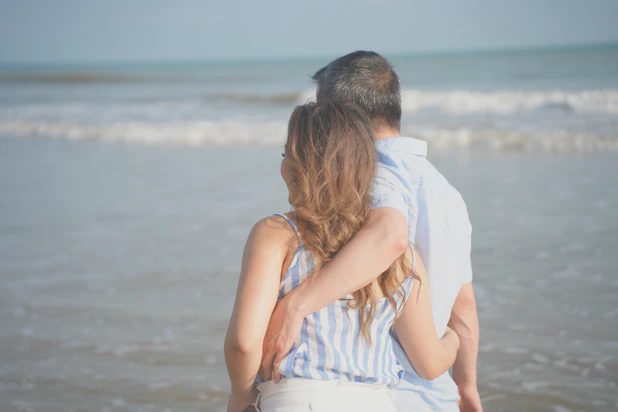 a man and woman kissing on a beach