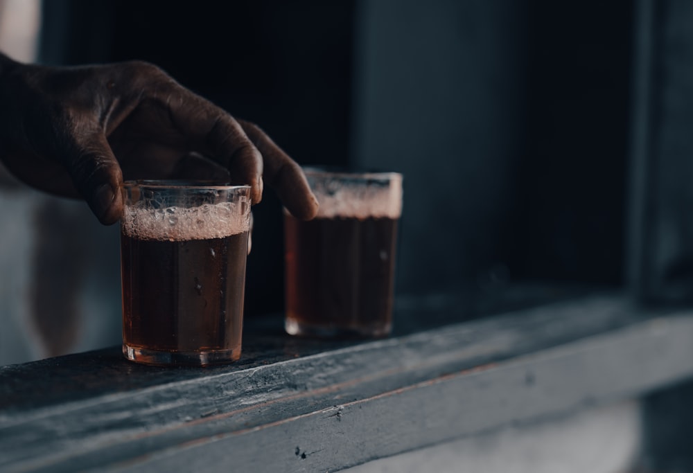 a hand holding a glass of liquid