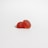 Two red gummy candies shaped like raspberries are placed on a clean, white surface. The candies have a translucent appearance with a glossy finish, displaying a bumpy texture resembling fruit details.