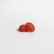 Two red gummy candies shaped like raspberries are placed on a clean, white surface. The candies have a translucent appearance with a glossy finish, displaying a bumpy texture resembling fruit details.