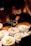 A chef is carefully plating dishes under warm lighting. Each white plate is topped with ravioli in a creamy sauce and garnished with fresh herbs. The chef uses a spoon to add sauce with precision, demonstrating attention to detail and culinary skill.