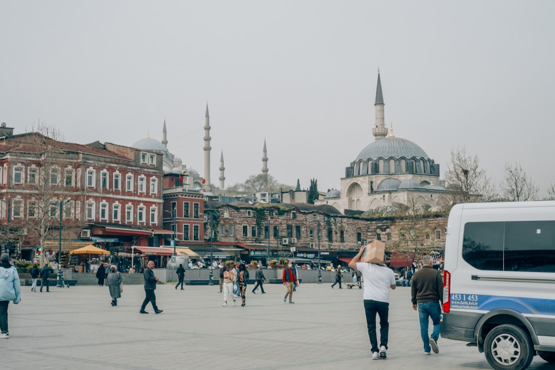 a group of people walking in a plaza with buildings in the background,