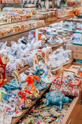 Shelves filled with intricately designed and colorful ceramic figurines, including animals and various decorative items. The assortment features a range of patterns and colors in a shop setting.