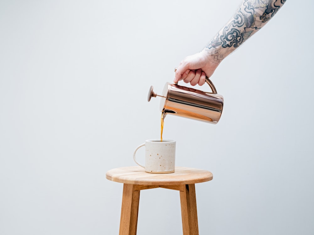 a hand pouring a cup of coffee