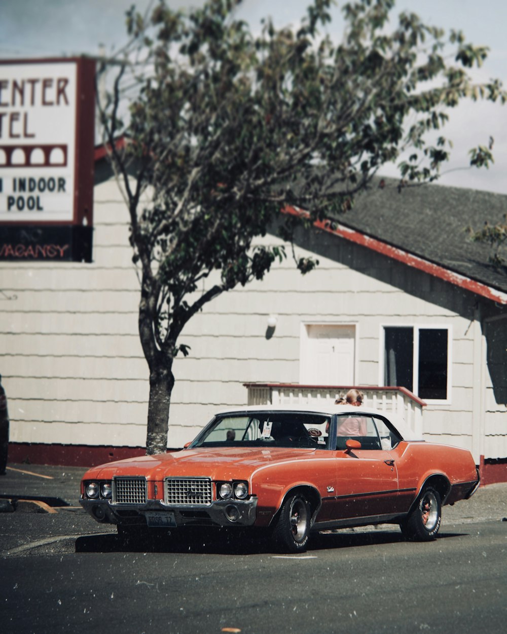 an orange car parked in front of a white building