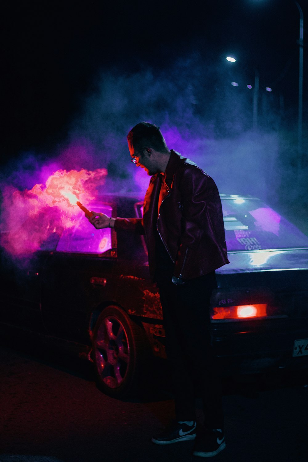 a man standing next to a car on fire