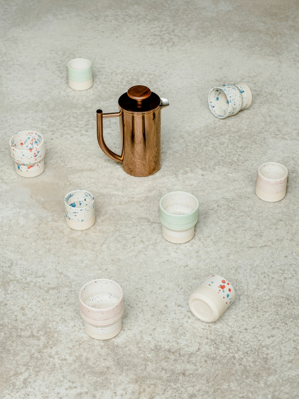 a group of white cups and a brown cylindrical object on a grey surface