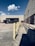 A delivery truck parked in front of a modern warehouse under a clear blue sky.
