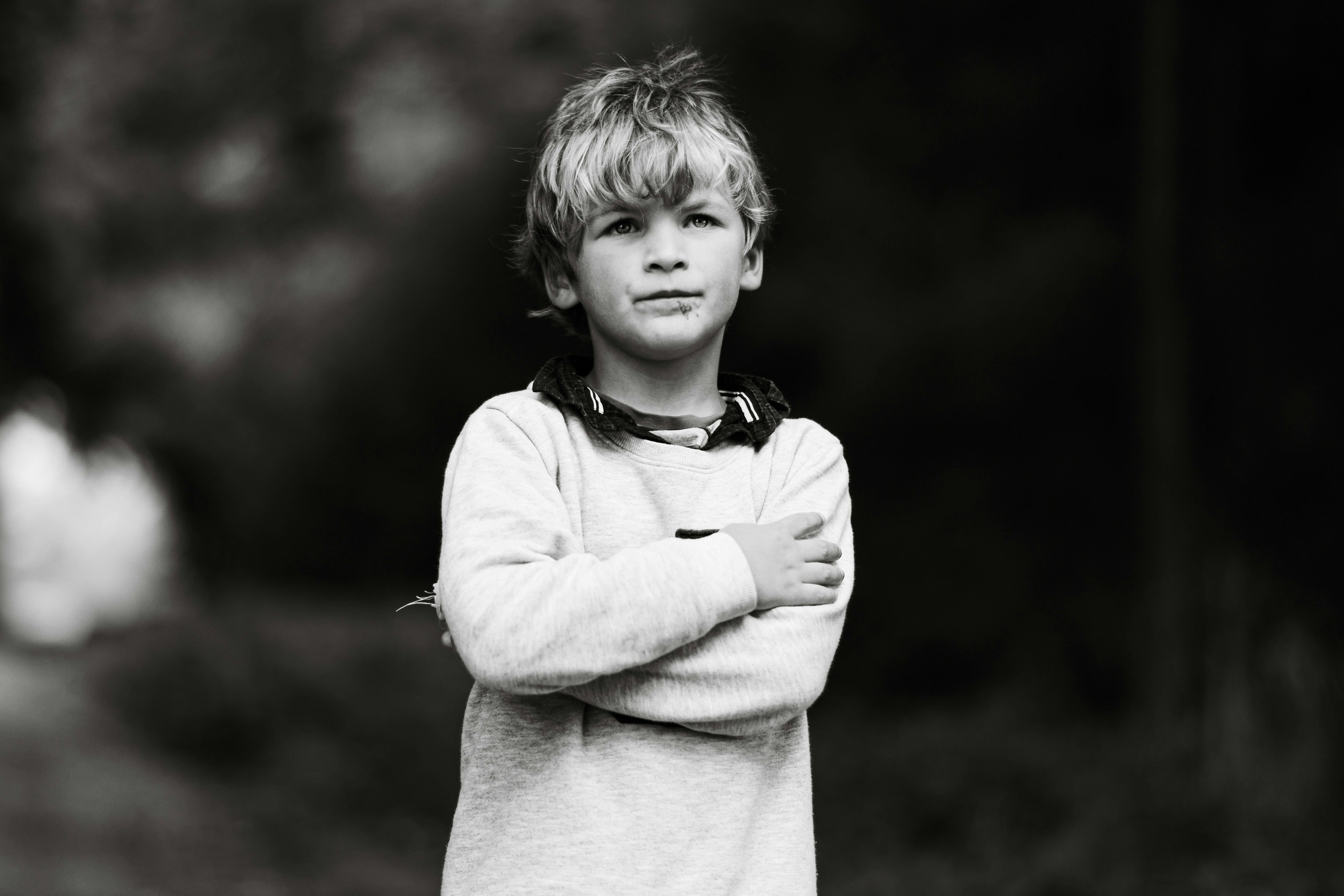 A young boy with arms crossed looking away.