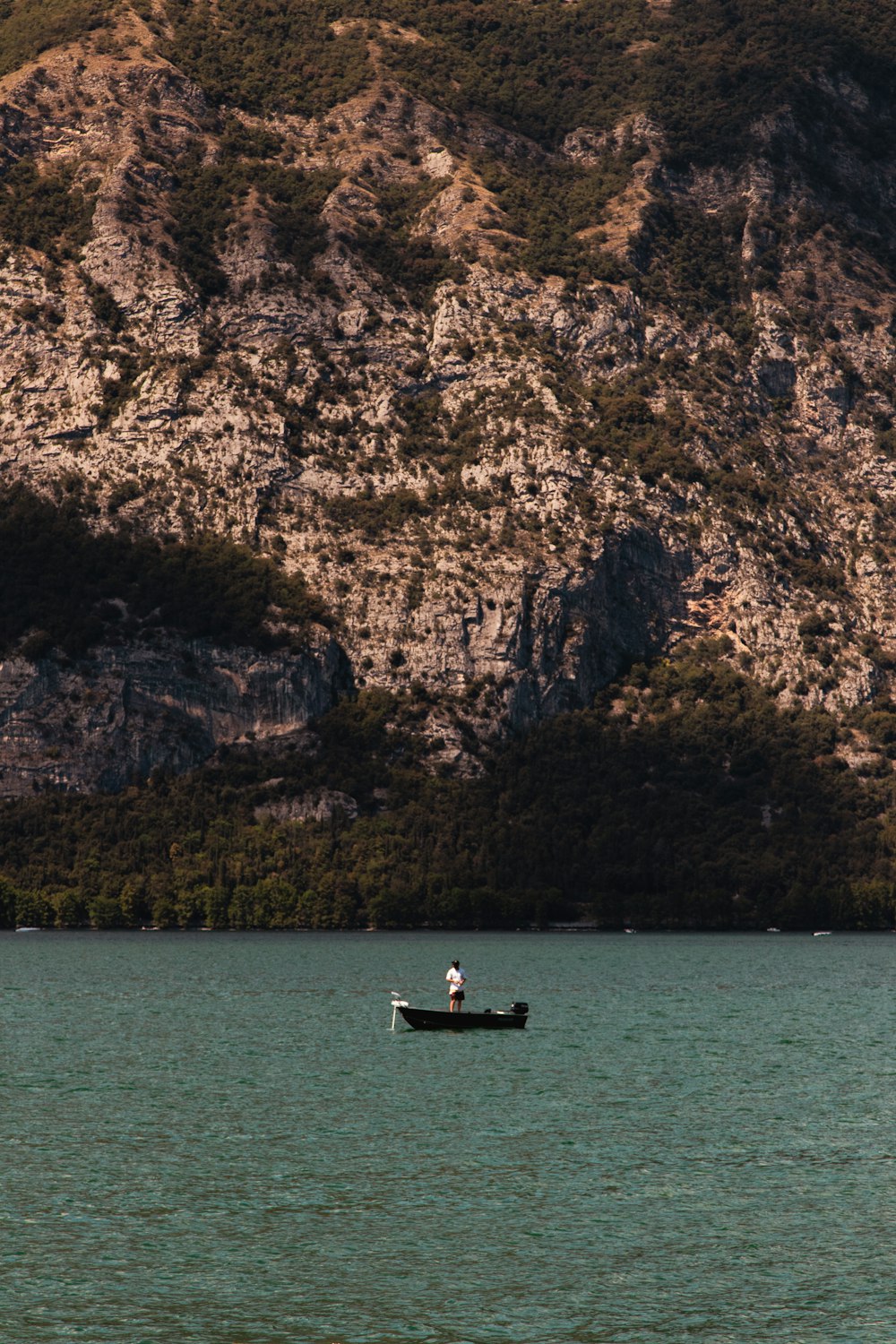 a person in a boat in the water by a cliff