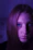 Close-up of a woman smiling with beautifully extended eyelashes in soft purple lighting.