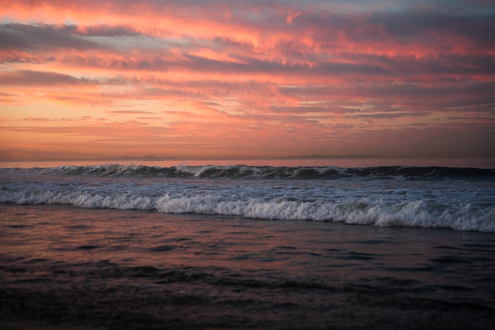 a beach with waves and a sunset