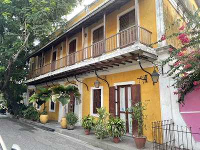 A charming colonial-style house in Mérida with colorful walls and lush greenery.