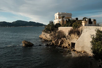 Stone-accented island house surrounded by natural greenery and vast ocean horizon under a clear sky.