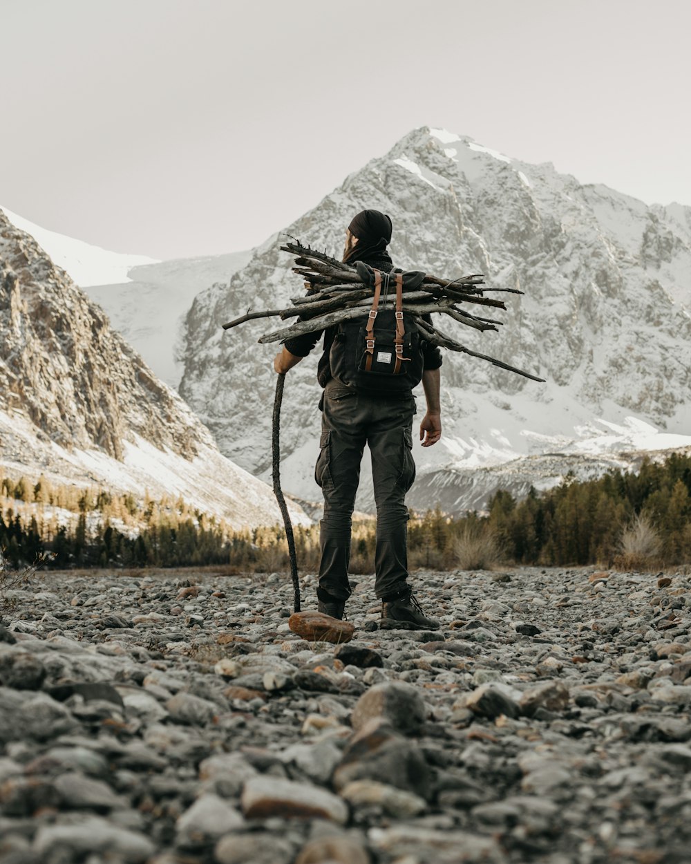 a man with a backpack standing on a rocky area with a mountain in the background