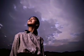 A cinematic still of a young protagonist caught in a moment of quiet reflection at sunset.