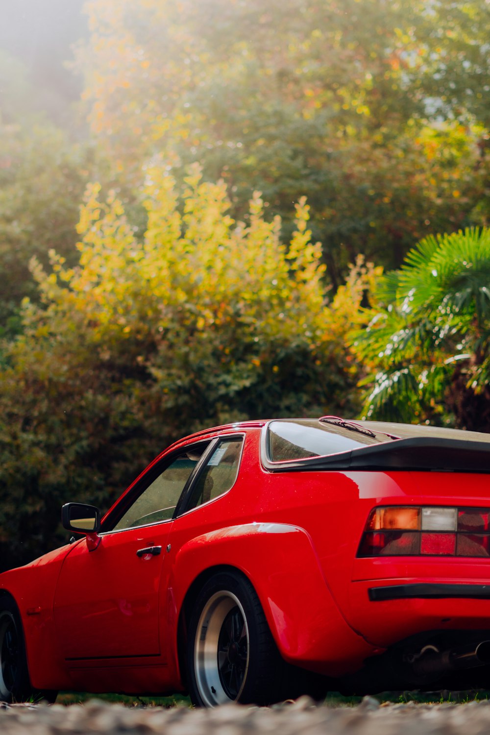 a red car parked in front of trees