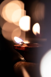 Close-up of a glowing diya lamp with soft bokeh in the temple courtyard at dusk