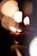A serene photo of a person lighting a diya in a softly lit temple corner.
