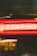 Neon lights create a dynamic blur of red and yellow colors, with visible text above offering motivational phrases. The lights suggest a storefront or a bar, with a lively atmosphere. Background elements include posters or signage, partially visible through the motion.