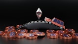 A small toy-like car is climbing up a curved, metallic surface. Below the curved surface are numerous copper-colored coins with the letter 'D' on them. Above the car, a geometric object resembling the Ethereum logo is floating.