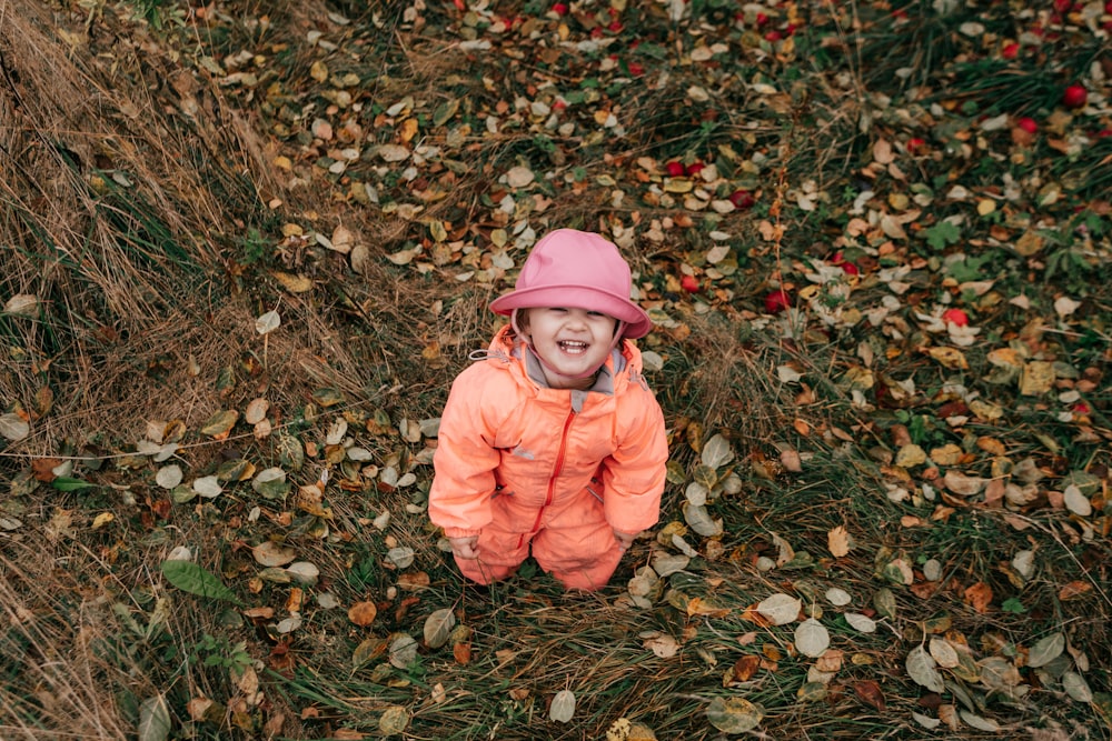 a child in a pink jacket in a field of leaves