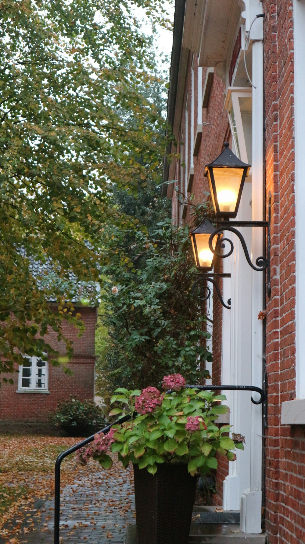 a lamp post next to a brick building with a tree and a fence