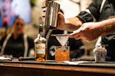 a person pouring a drink into a glass