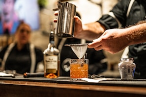 a person pouring a drink into a glass