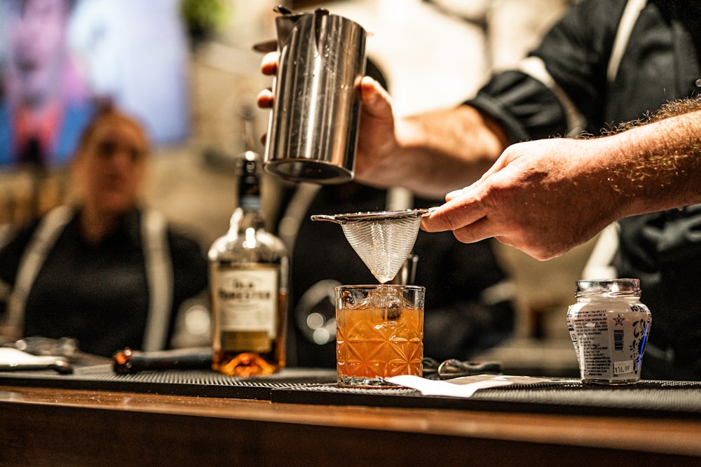 a person pouring a drink into a glass