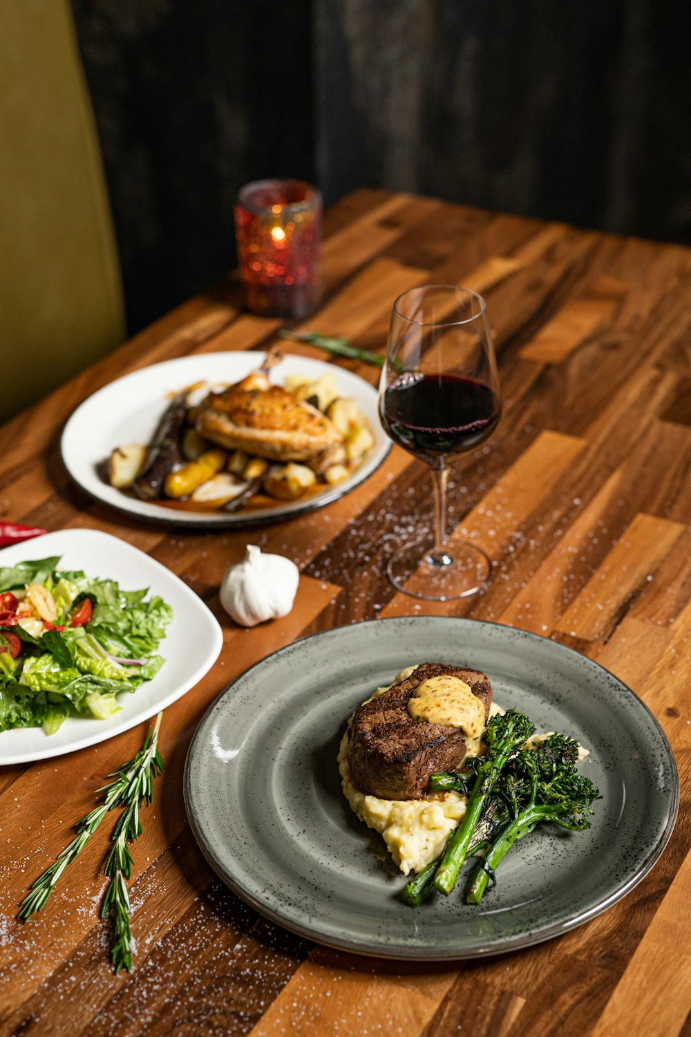 a table with plates of food and a glass of wine