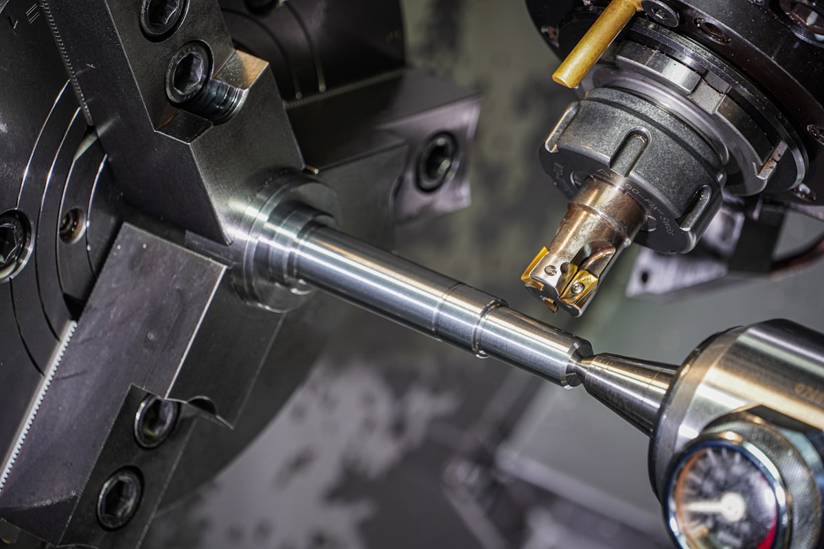 Mesin CNC bubut presisi sedang mengerjakan poros logam di sebuah bengkel machining