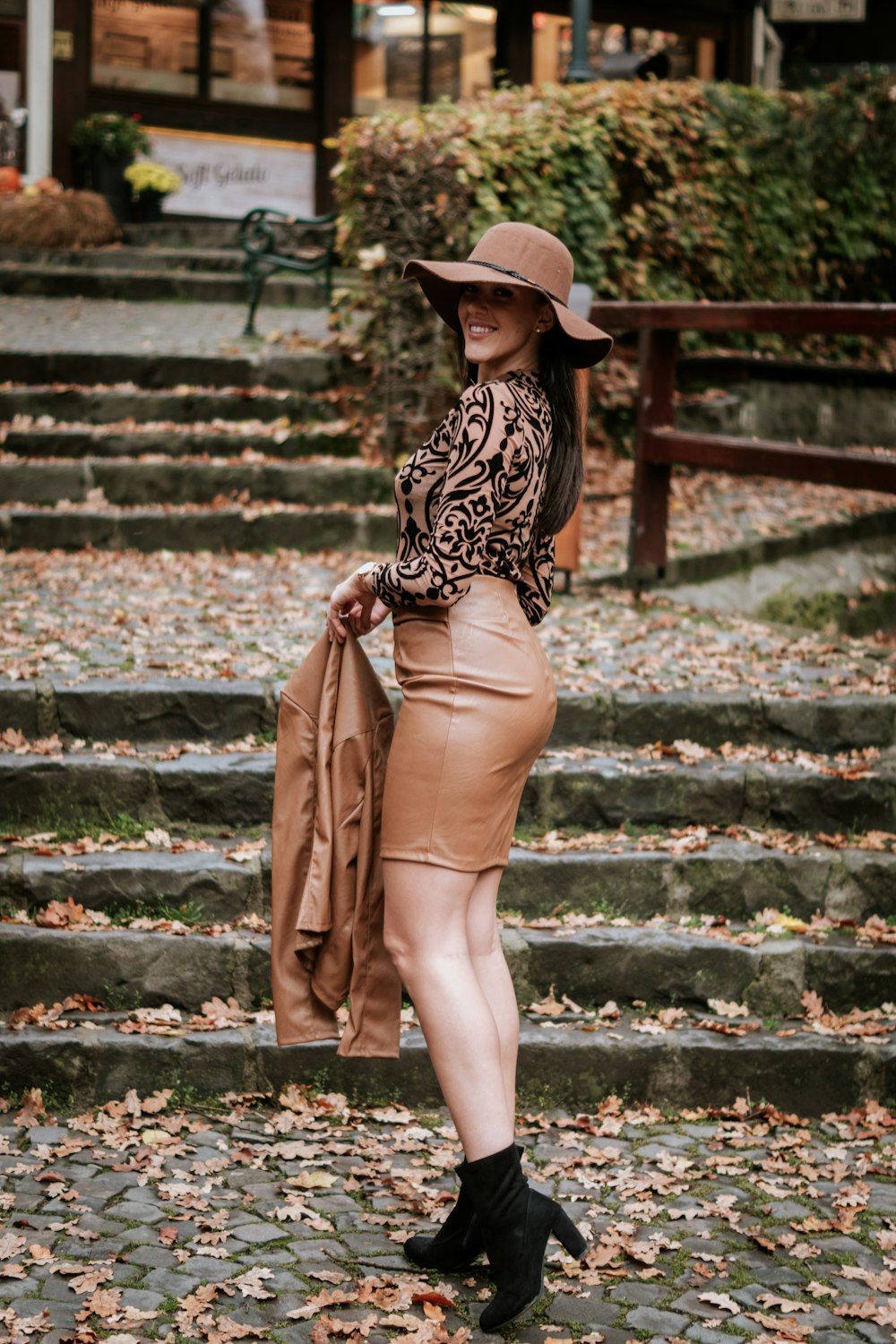 a woman wearing a hat and standing on a stone staircase