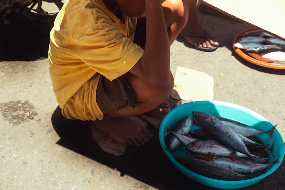 Una persona sentada en el suelo con un pez en las manos