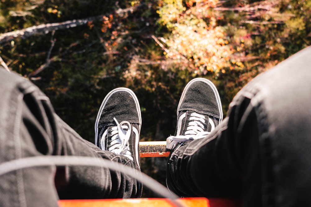 a pair of feet in black shoes on a tree branch