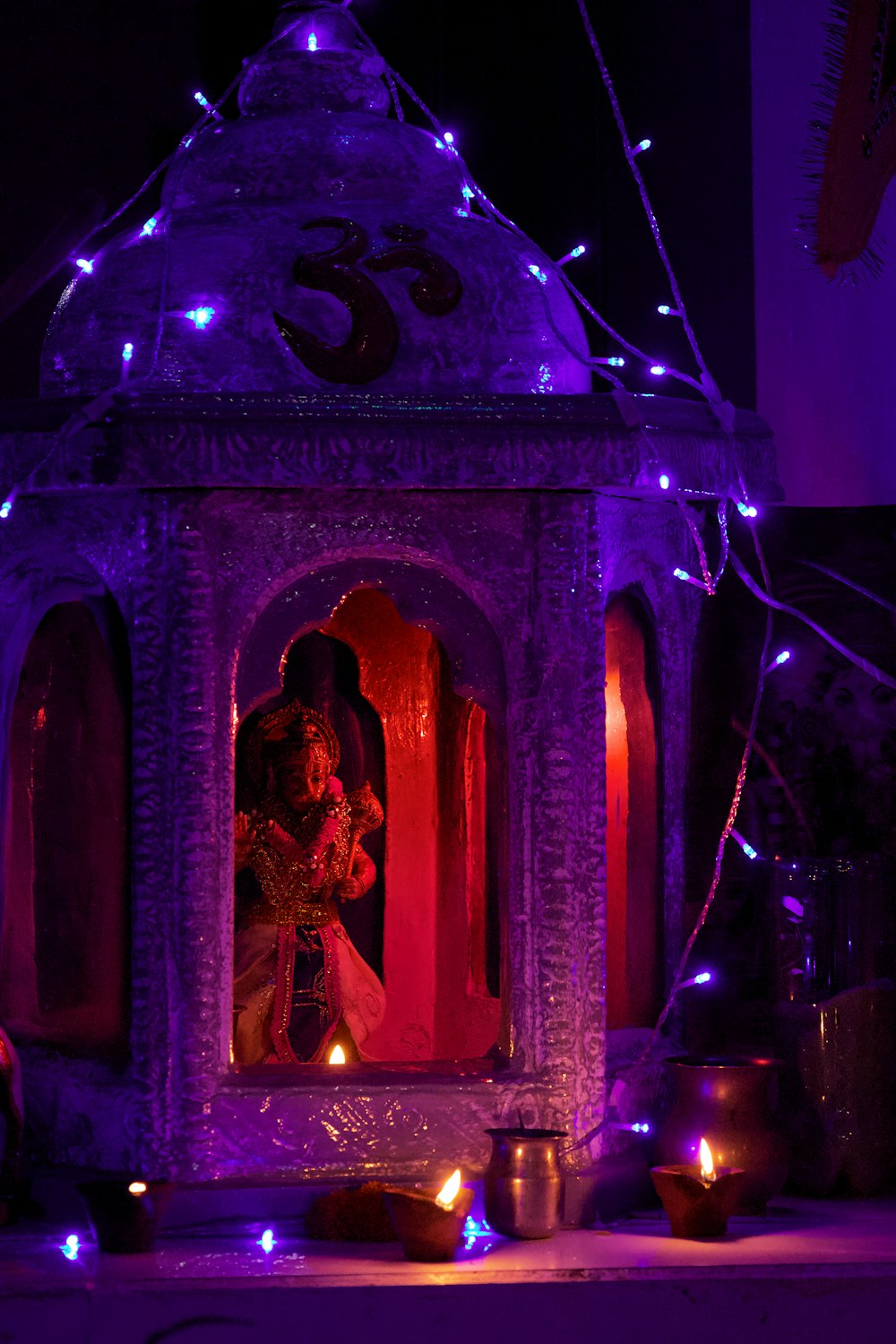 a statue in a purple room with candles and a large purple and pink building