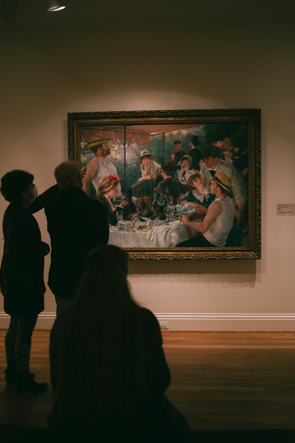 a group of people looking at a painting on a wall