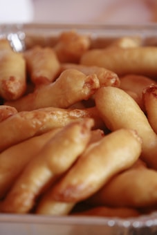A container filled with several pieces of golden-brown fried food, likely representing a type of snack or appetizer. The food items have a smooth and slightly glossy texture, indicating they are freshly fried.