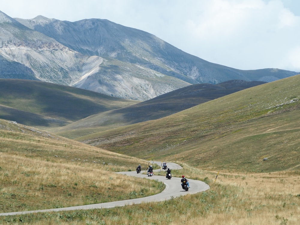 a group of people riding motorcycles on a road in a valley