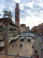 Bustling Piazza delle Erbe with colorful market stalls and lively crowds.
