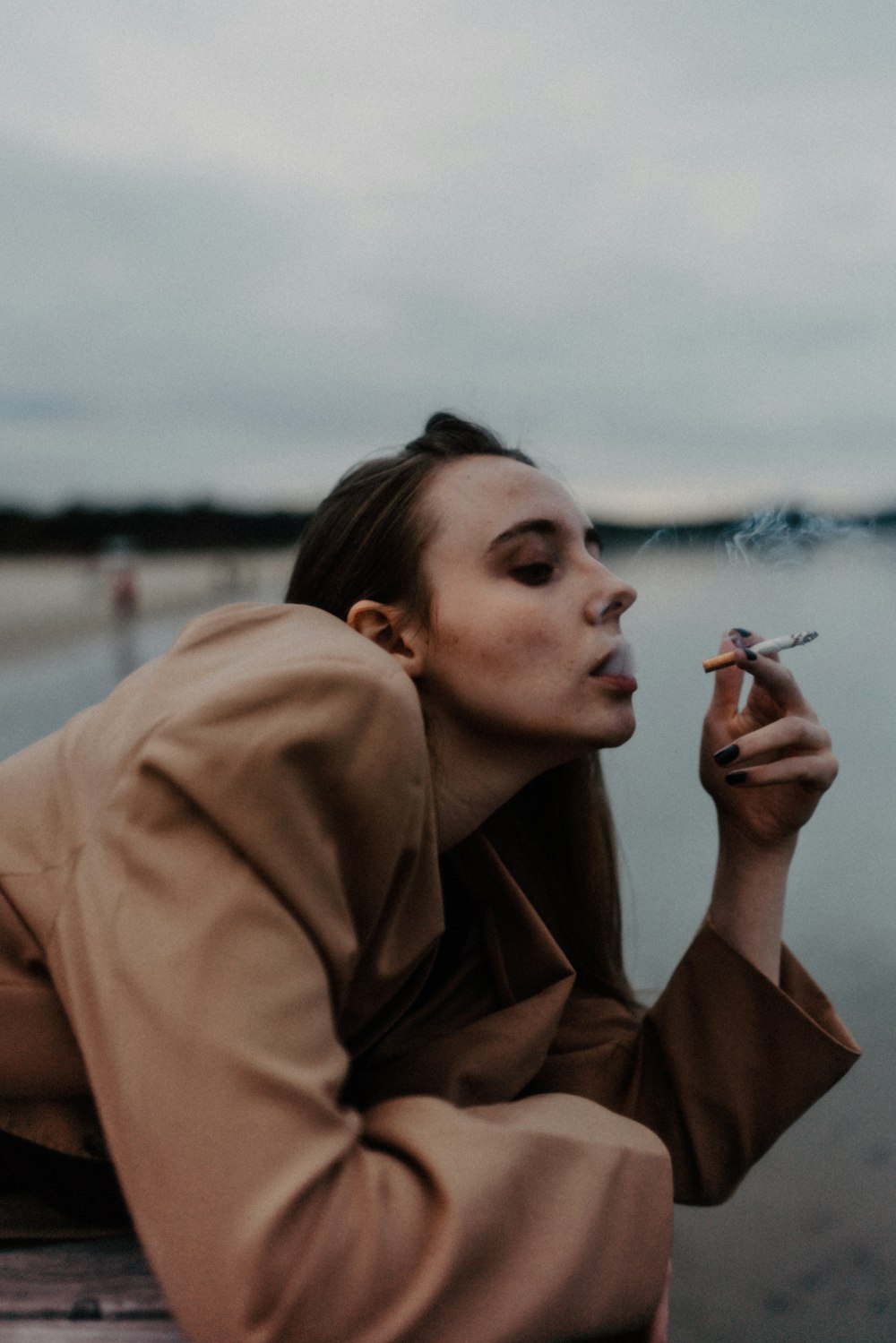 a woman smoking a cigarette on a beach
