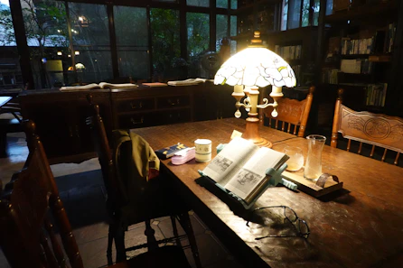 A cozy reading nook bathed in soft afternoon light, with an open book resting on a wooden table.