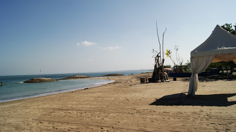 una playa con una tienda de campaña y un cuerpo de agua