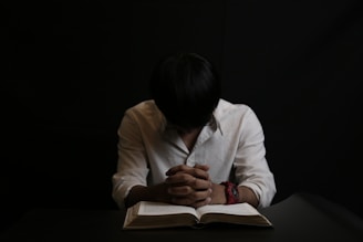 A professional white-collar worker reading 'The Handbook of Employee Self-Defense' with focused concentration under soft lighting.